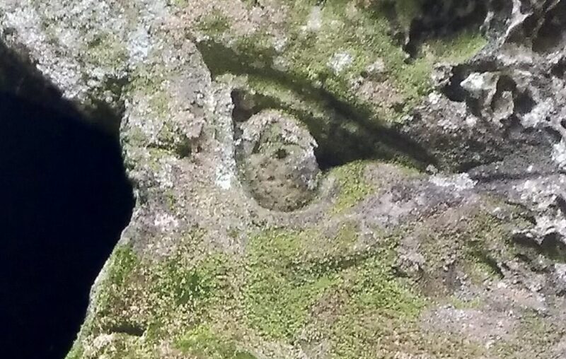 In einen Felsen gehauene Seitenansicht eines Gesichts mit traurig-wütendem Blick